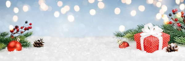 Красный подарок в снегу с новогодними украшениями — стоковое фото