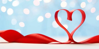 Mavi arka planda kalp şeklinde kırmızı kurdele. Sevgililer Günü kartı