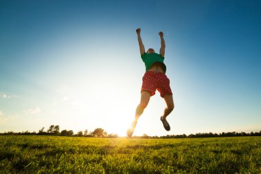 genç adam karahindiba ile çayır üzerinde atlama