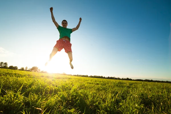 Jeune homme sautant sur la prairie avec des pissenlits — Photo