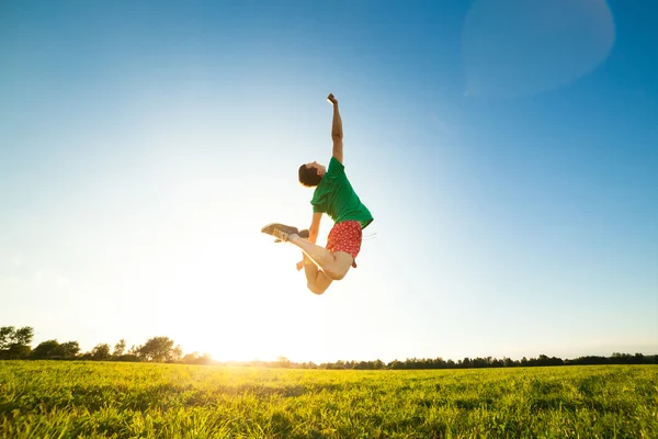 Молодой человек прыгает по лугу с одуванчиками — стоковое фото