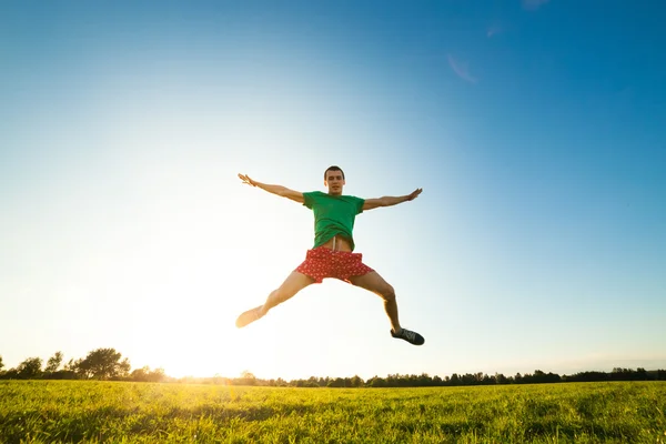 Young man jumping on meadow with dandelions — Stock Photo, Image