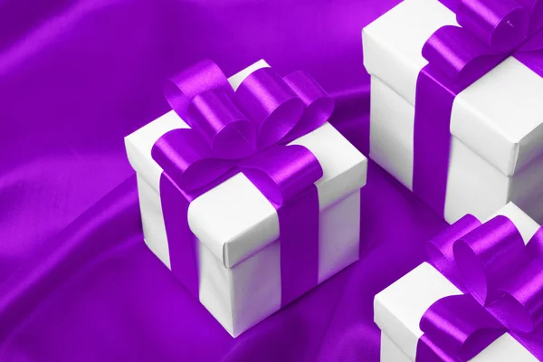 Подарок на фиолетовом фоне атласа — стоковое фото