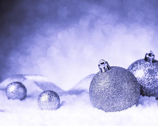 Julgranskulor i snö på glitter bakgrund — Stockfoto