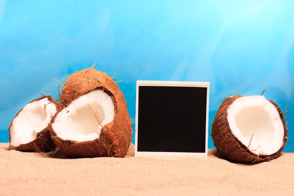 Coco picado y fotomarco en la arena —  Fotos de Stock