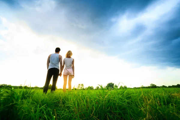 Couple walking through the field and holding hands — Stock Photo, Image