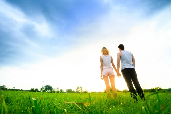 Par promenader genom fältet och hålla händer — Stockfoto