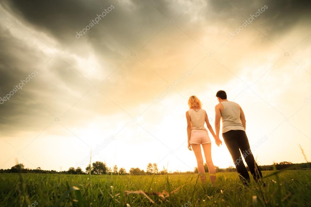 couple walking through the field and holding hands