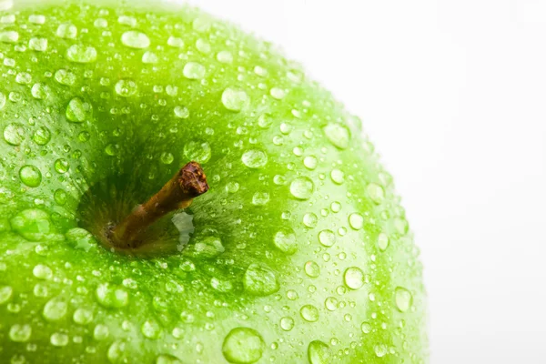 Яблоко в зеленом с каплями воды на его поверхности — стоковое фото