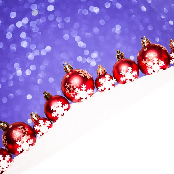 Bolas rojas de Navidad en la nieve sobre fondo de brillo azul — Foto de Stock