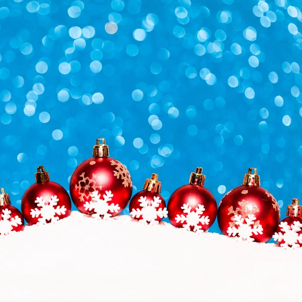 Рождественские красные шары в снегу на голубом фоне блесток — стоковое фото
