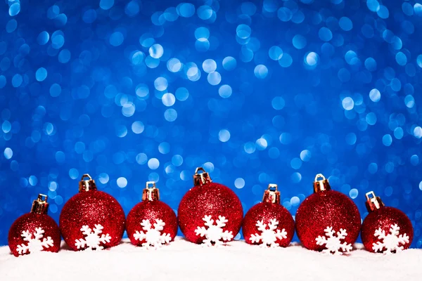 圣诞红球在雪上蓝色光圈背景 — 图库照片