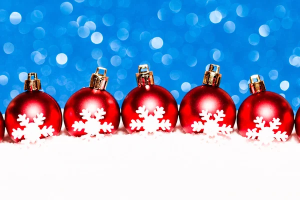 Rode kerstballen in sneeuw op de achtergrond blauw glitter — Stockfoto