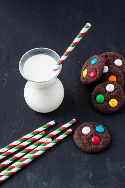 Chocolate cookies with sugar coated candy and milk — Stock Photo, Image