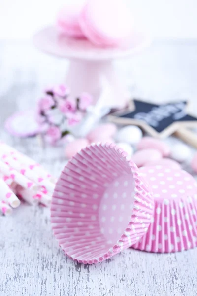 Dulces recubiertos de azúcar, tazas para hornear magdalenas, macarrones, pajitas rosadas — Foto de Stock