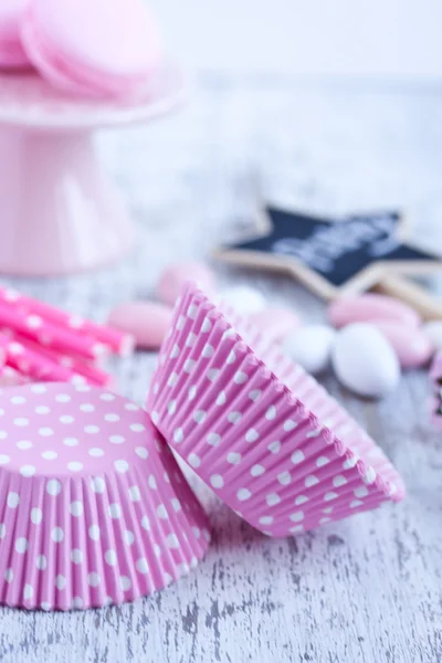 Dulces recubiertos de azúcar, tazas para hornear magdalenas, macarrones, pajitas rosadas —  Fotos de Stock