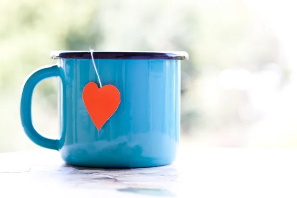 Enamel cup with heart shape teabag — Stock Photo, Image