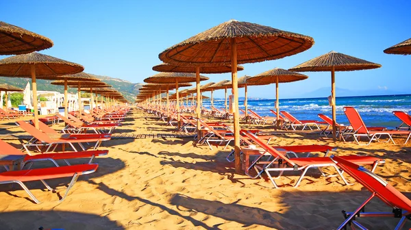 Laganas, Griekenland - 23 Aug 2015: Paraplu's en zonneterrassen van het zandstrand van de banaan op Zakynthos, Griekenland. Banaan is het grootste strand van Zakynthos eiland. — Stockfoto