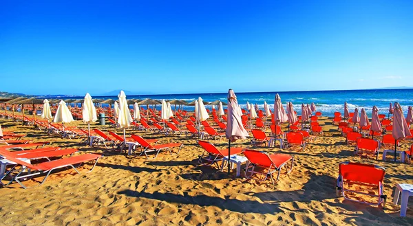 Laganas, Griekenland - 23 Aug 2015: Paraplu's en zonneterrassen van het zandstrand van de banaan op Zakynthos, Griekenland. — Stockfoto