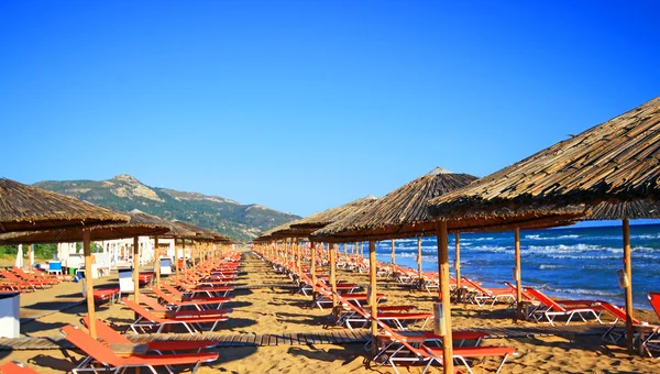 Paraplu's en zonneterrassen van het zandstrand van de banaan op Zakynthos, Griekenland. Banaan is het grootste strand van Zakynthos eiland. — Stockfoto