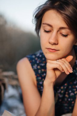 Buğday tarlasında kitap okuyan kız.