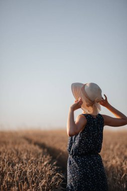 Buğday tarlasında şapkalı bir kız.