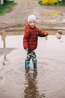 Çizmeli bir çocuk su birikintilerinde yürüyor.