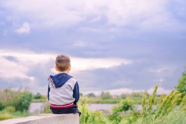 Çocuk nehrin kenarında, çocuk güzel bir gökyüzünün arka planında