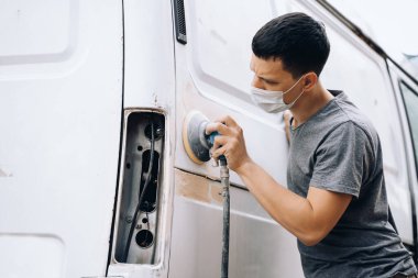 Vücut tamiri, aletleri olan bir adam araba tamir eder.