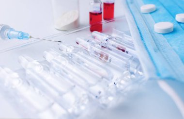 Beyaz masada bir şırınga ve bir sıra ilaç var. Yatay bileşim. Önplan.