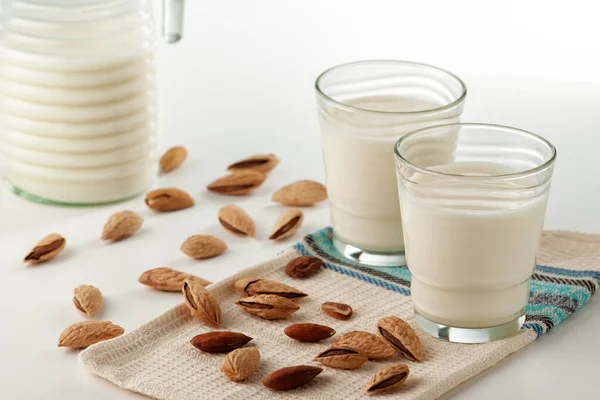 On a white table, almond milk in a glass with almonds