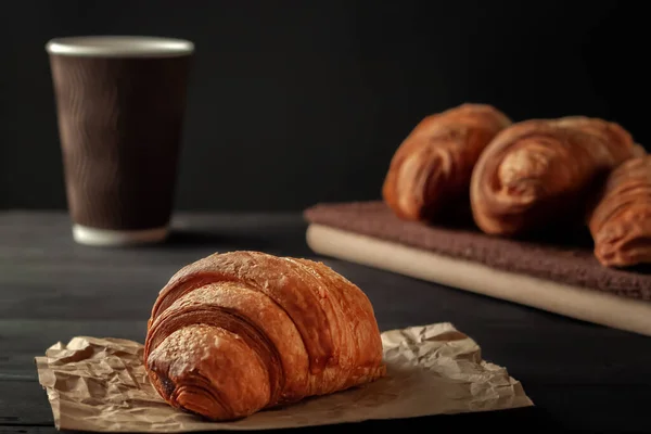 Tasse Cappuccino und Croissant auf dunklem Tisch — Stockfoto