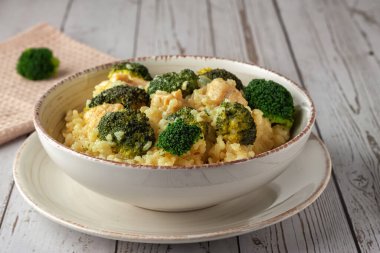 Tahta arka planda tavuk ve brokolili kremalı risotto.