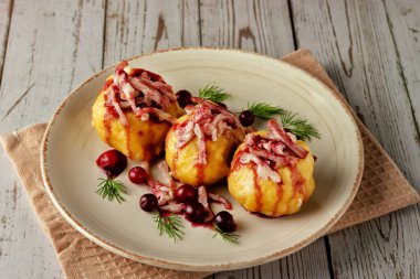 Hafif arkaplanda kızılcık soslu İsveç patatesli börek.
