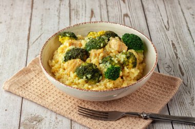 Tavuklu kremalı risotto ve ahşap arka planda bir tabakta brokoli.