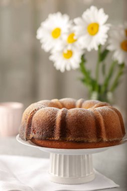 Yuvarlak kek, beyaz tepside bir delik, üzerine pudra şekeri serpiştirilmiş.