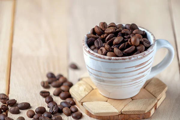 Grains de café torréfiés dans une tasse en céramique. Image symbolique. Espace de copie. — Photo