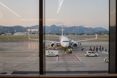 Milano Bergamo Uluslararası Havaalanı 'nın biniş alanında kuyrukta bekleyen insanları pencereden izliyoruz. Uçuş görevlileri, yolculara sosyal mesafeli davranma kurallarını uyguladıklarından emin olun. Coronavirüs zamanında seyahat ve turizm kavramı.