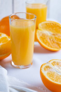 Bir bardak taze sıkılmış portakal suyu ve ışık masasında dilimlenmiş portakal suyu.