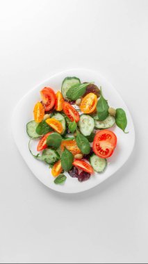 Açık arkaplanda taze sebze ve sebze salatası ile beyaz tabak.