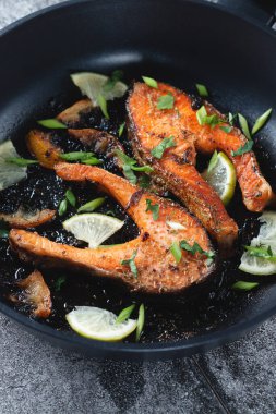 Limonlu, baharatlı ve limonlu ızgara somon bifteği ve kireç, kayrak taşı bir masada, yakın plan. Lezzetli pişmiş somon filetosu.