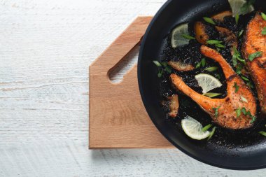 Limonlu, baharatlı ve limonlu ızgara somon bifteği. Hafif ahşap bir masada tavada. Lezzetli pişmiş somon filetosu.