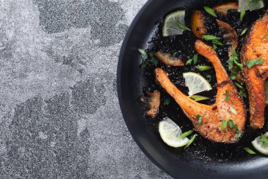 Limonlu, baharatlı ve limonlu ızgara somon bifteği ve kireç, kayrak taşı bir masada, yakın plan. Lezzetli pişmiş somon filetosu.