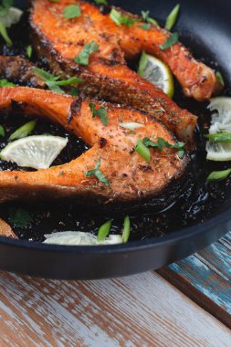 Limonlu, baharatlı ve limonlu ızgara somon bifteği. Hafif ahşap bir masada tavada. Lezzetli pişmiş somon filetosu.