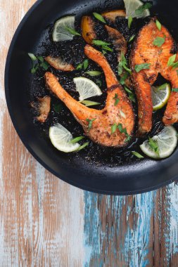 Limonlu, baharatlı ve limonlu ızgara somon bifteği. Hafif ahşap bir masada tavada. Lezzetli pişmiş somon filetosu.