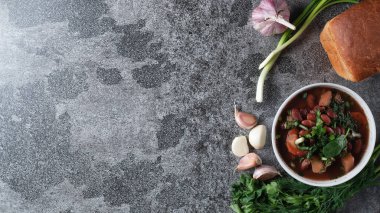 Beyaz bir kasede otlu fasulye çorbası taze çavdar ekmeği ve sarımsak ile koyu bir arka plan, üst manzara, metin için yer.