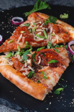 Geleneksel İtalyan biberli pizzasını domatesli, peynirli, uçan soğanlı ve otlu dilimler.