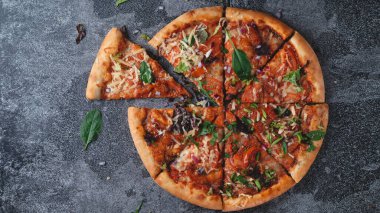 Geleneksel İtalyan biberli pizza. Domatesli, peynirli, soğanlı ve bir sürü otlu. Koyu bir masa üzerinde.