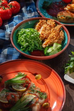 Açık büfede sebze ve salatalıklı kil tabakta tavuk nugget.