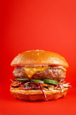 Kırmızı arka planda lezzetli bir burger. Peynirli lezzetli ve sağlıksız hamburgerler. Fast food, abur cubur kavramı.